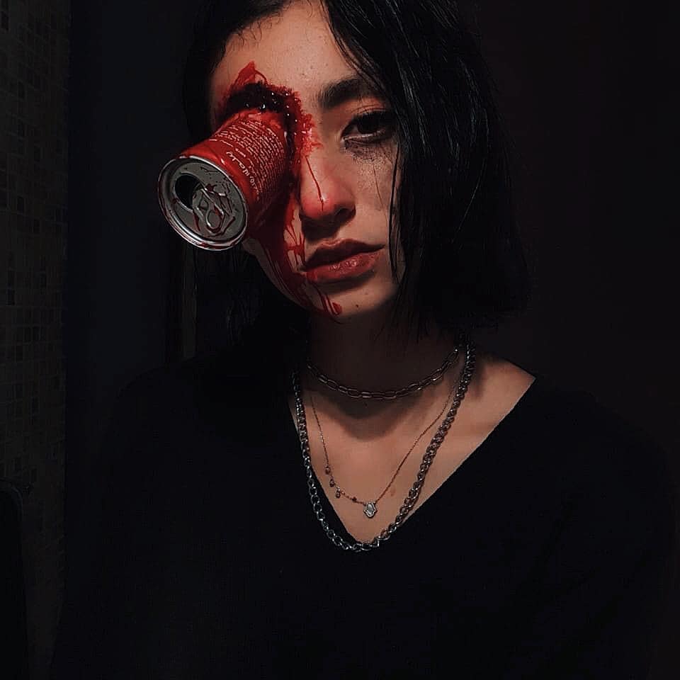 Practical-effects makeup with a crushed can embedded at the eye and theatrical blood